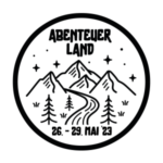 Schwarz-weißes Logo zum Bezirkslager 2023. Auf dem Logo steht oben "Abenteuerland" und unten "26. - 29. Juni '23", in der Mitte sind mehrere Berge zu sehen, durch die ein Fluss läuft. Vorne stehen einige Tannenbäume und im Hintergrund sind Sterne am Himmel zu sehen.
